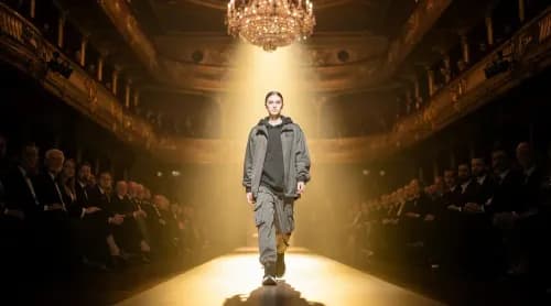 Model läuft Runway in historischem Theatersaal, Publikum sitzt wie eine Jury