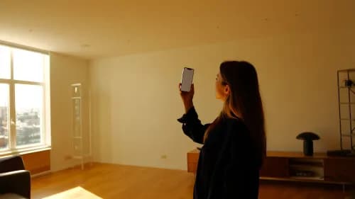 Frau nutzt Augmented Reality per Smartphone zur Möbelplatzierung im Wohnzimmer