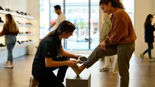 Verkäuferin scannt Kundenfuß im modernen Store für individuelle Produktempfehlung