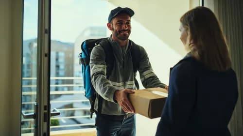 Kurier übergibt Paket an Kundin an moderner Haustür im Tageslicht
