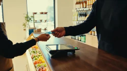 Ladeninhaberin gibt Kundin Zahlungskarte an modernem Kartenterminal im Geschäft zurück