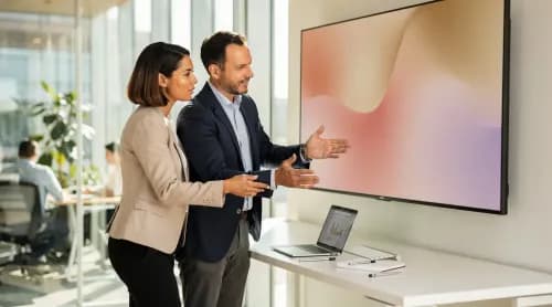 Zwei Consultants besprechen CRM-Strategie an großem Bildschirm im modernen Büro