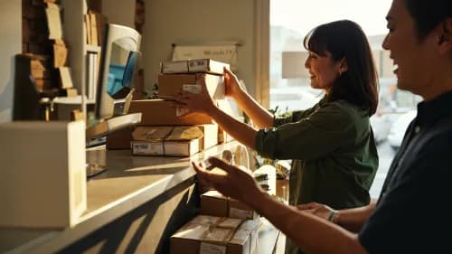 Kundin holt gebündelte Pakete an urbanem Abholpunkt ab – Konzept von Paketconcierge